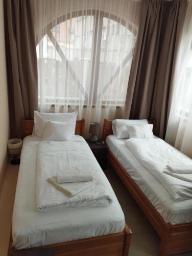 two beds in a room with a window at Régi Posta Hotel és Étterem in Debrecen