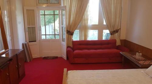 a living room with a red couch in front of a window at Aman E Yal in Gilgit