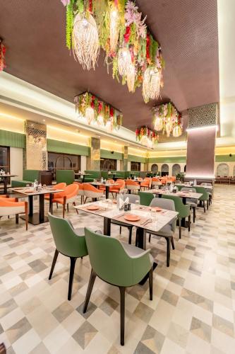 a restaurant with tables and chairs and chandeliers at Pravasa Hotel Vijayapura in Bijāpur