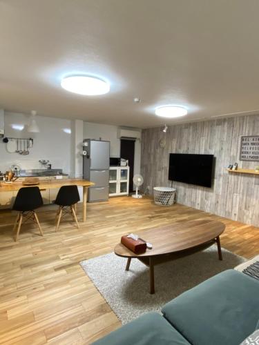 Una sala de estar con una mesa y una cocina. en プチリゾート・ひじきwest, en Hijiki