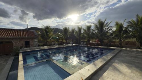a large swimming pool with palm trees in the background at Pousada de Campo Estância Bahamas in Pirenópolis