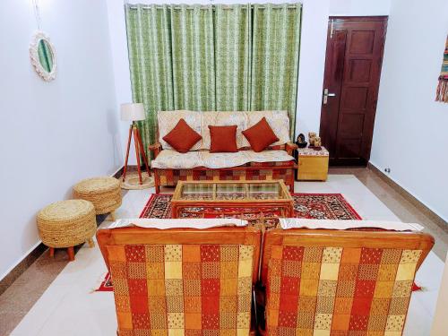 a living room with a couch and some pillows at Whispering Meadows U get entire 3 BHK in Shimla