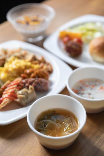 a table with plates of food and bowls of soup at With Stay Jeju Hotel in Jeju