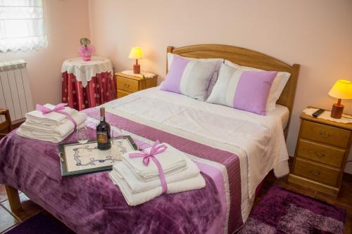 Una cama con toallas y una bandeja con una botella de vino. en Escondidinho do Vez, LDA, en Arcos de Valdevez