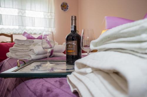 a glass table with a bottle of wine and two glasses at Escondidinho do Vez, LDA in Arcos de Valdevez