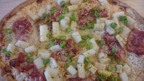 a pizza with cheese and pepperoni and green onions on it at Hotel Restaurant Jägerhof in Braunschweig