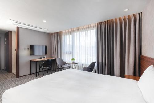 a hotel room with a large bed and a desk at With Stay Jeju Hotel in Jeju