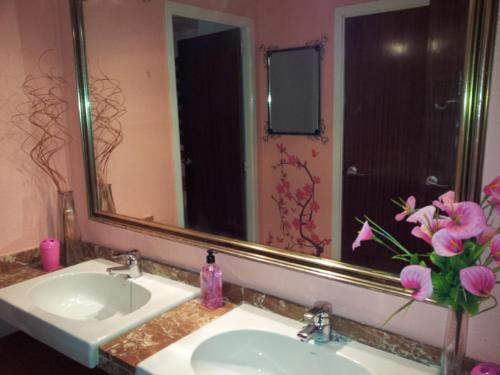 a bathroom sink with a mirror and a vase of flowers at Valparaiso Seafront in Cunit