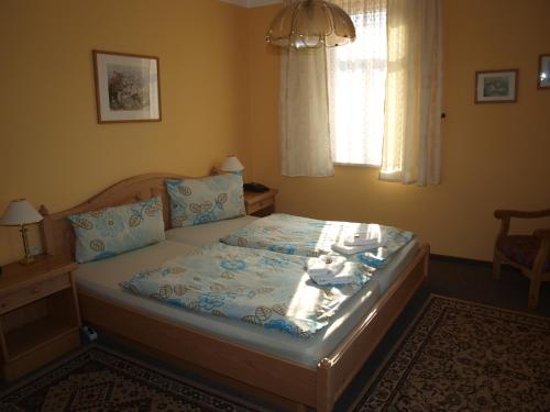 a bedroom with a bed with blue sheets and a window at Gasthof zur Schweiz in Jena