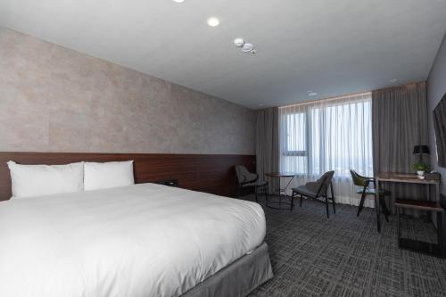 a hotel room with a bed and a desk at With Stay Jeju Hotel in Jeju