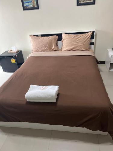 a bed with a brown blanket and a white towel on it at สุวรรณภูมิอพาร์ทเม้นท์ in Suvarnabhumi Airport