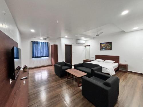 a hotel room with a bed and a couch and chairs at Tripura Inn in Nalgonda