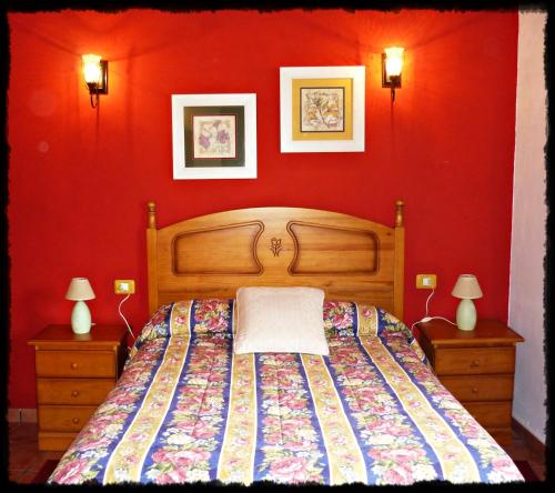 een slaapkamer met een bed en een rode muur bij Casa Rural Amasín in Valverde