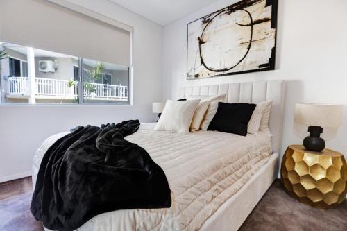a bedroom with a white bed with a black blanket on it at The Strand Stunner in North Ward