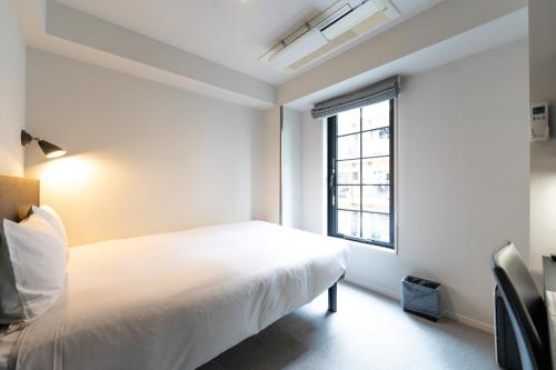 a bedroom with a white bed and a window at HOTEL TABARD TOKYO in Tokyo