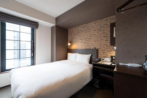 a bedroom with a white bed and a brick wall at HOTEL TABARD TOKYO in Tokyo