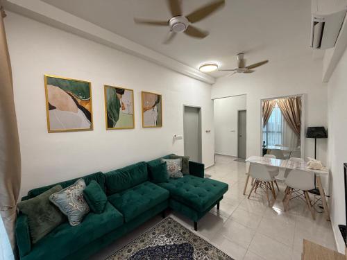 Una sala de estar con un sofá verde y una mesa. en Little Heaven Homestay Nilai, en Nilai