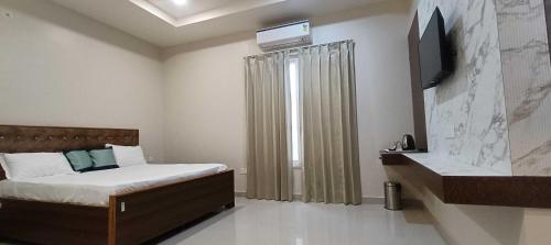 a bedroom with a bed and a tv on the wall at Hotel O Shagun hotel and Banquets in Gomti Nagar