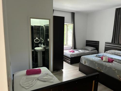 a bedroom with two beds and a sink and a mirror at Bujtina Lecaj in Selcë