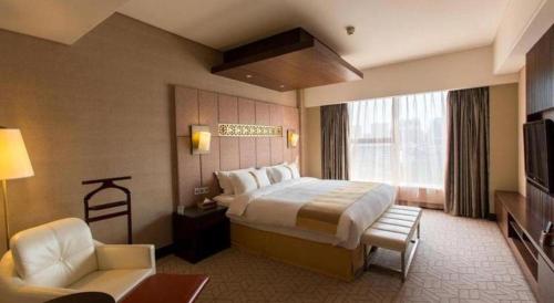 a hotel room with a large bed and a chair at Datong Hotel in Datong