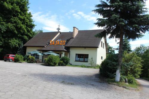 une maison blanche avec un toit noir et un arbre dans l'établissement Zajazd Podlesie, à Chociwel
