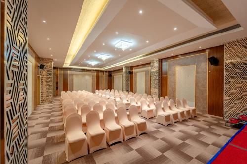 an empty conference room with white chairs in it at Pravasa Hotel Vijayapura in Bijāpur