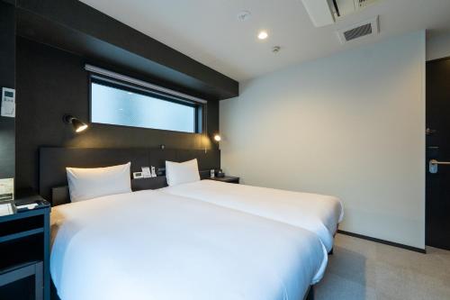 a large white bed in a room with a window at HOTEL TABARD TOKYO in Tokyo