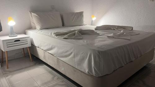 a white bed with two pillows and a night stand at LAINAS apartments in Nea Skioni