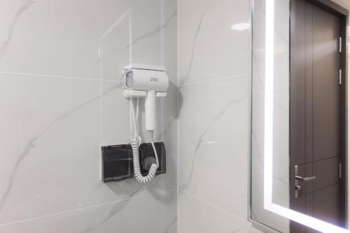 a white bathroom with a hair dryer on a wall at Comfy Quite Private Room with Private Balcony - Hulhumale in Hulhumale