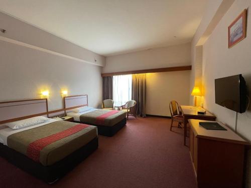 a hotel room with two beds and a television at Hotel Grand Continental Kuantan in Kuantan