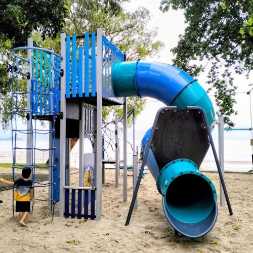 a boy is playing on a blue playground equipment at Willow Garden Stays Cairns - Beachfront 4 Bedroom Luxury Holiday Home in Kewarra Beach