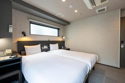 a large white bed in a room with a window at HOTEL TABARD TOKYO in Tokyo