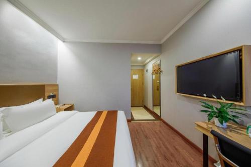 a hotel room with a large bed and a flat screen tv at GreenTree Inn Jiaxing Tongxiang Tudian Express Hotel in Jiaxing