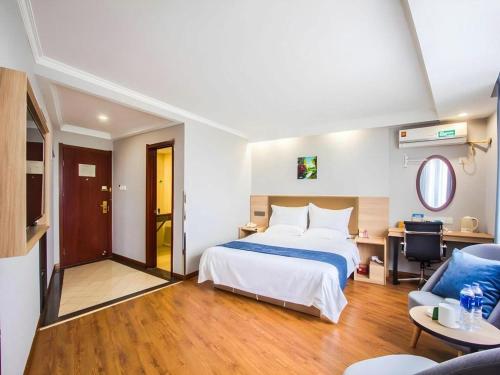 a hotel room with a bed and a desk at GreenTree Inn Jiaxing Tongxiang Tudian Express Hotel in Jiaxing