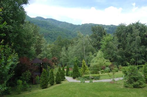 a garden with trees and a gazebo in the distance at Casa Lacului in Malaia