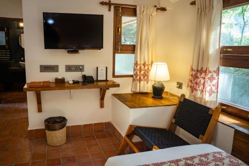 a room with a tv and a chair and a bed at Riverside Springs Resort in Chitwan