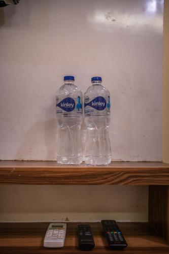 three bottles of water sitting on a shelf with remote controls at HOTEL AUGUSTO in Varanasi