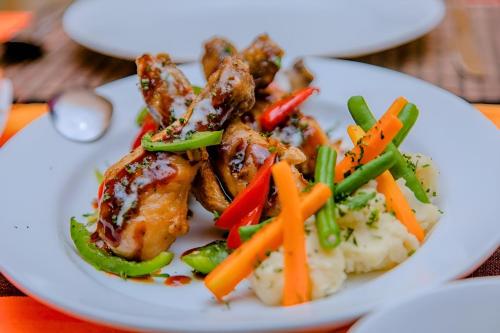 a plate of food with chicken and vegetables on a table at Bundala Bird View in Hambantota