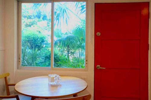 a red door and a table in a room with a window at St Jean studio steps away from the beach in Saint-Jean