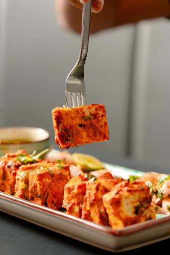 a person holding a piece of food on a fork at Pravasa Hotel Vijayapura in Bijāpur
