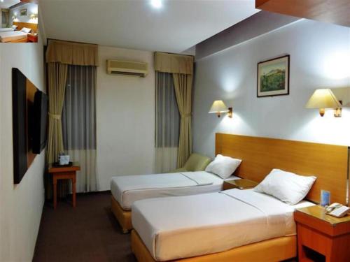 a hotel room with two beds and a television at Puri Mega Hotel in Jakarta