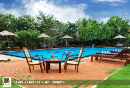 a table and chairs next to a swimming pool at Camellia Resort And Spa Sigiriya - Sri Lanka in Avudangawa