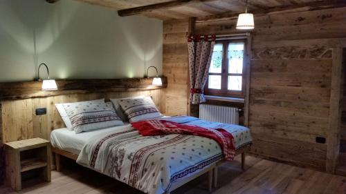 een slaapkamer met een bed met houten wanden en een raam bij Ospitalità rurale familiare Land Wasser in Varallo