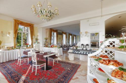 a dining room with tables and chairs and a kitchen at Lolli Palace Hotel in Sanremo