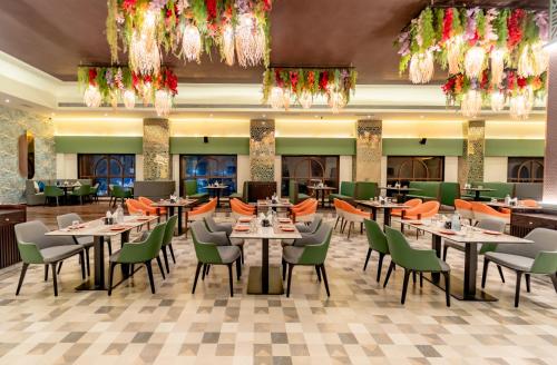 a restaurant with tables and chairs and chandeliers at Pravasa Hotel Vijayapura in Bijāpur