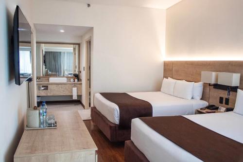 a hotel room with two beds and a bathroom at Clarion Suites Guatemala City in Guatemala