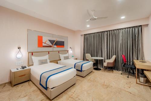 a hotel room with two beds and a desk at Pravasa Hotel Vijayapura in Bijāpur