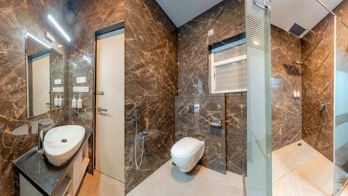 a bathroom with a toilet and a sink and a shower at Pravasa Hotel Vijayapura in Bijāpur