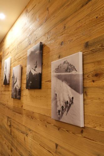 a wall with four pictures on a wooden wall at Leos Chalet in Valdaora di Sopra