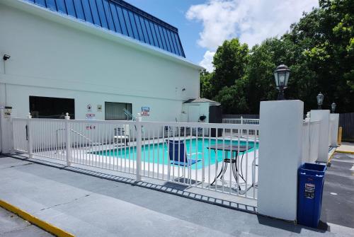 a white fence around a swimming pool next to a building at Days Inn by Wyndham Ocean Springs in Ocean Springs